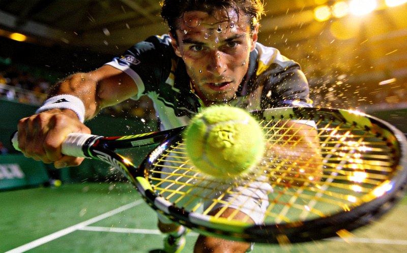网球大满贯比赛中，运动员奋力挥拍击球的瞬间特写